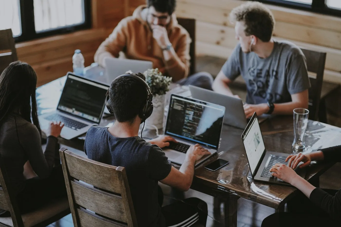 Group of people working together at laptops around a long table