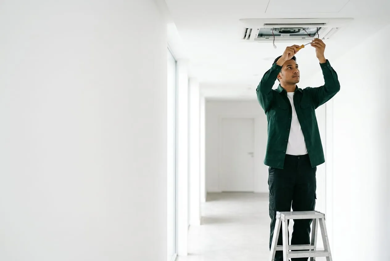 Field service technician working on building equipment in a bright white corridor