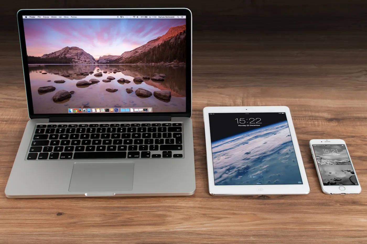 Laptop, tablet and phone side by side on a wooden desk